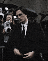 a man in a suit and tie standing in front of a crowd