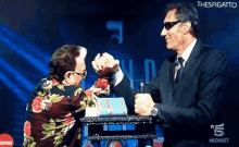 a man in a suit and tie is arm wrestling another man