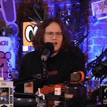 a man speaking into a microphone with a hoodie that says quited