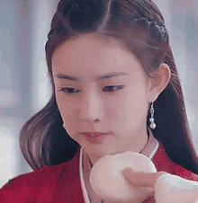 a woman in a red dress is holding a white item in her hand .