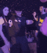 a group of people dancing in a dark room with purple lights