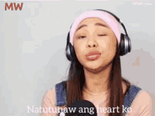 a woman wearing headphones is singing into a microphone and the words natutunaw ang heart ko are on the bottom
