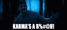 a man in a dark room with the words karma 's a b % # @ hi on the bottom