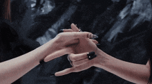 a woman with long black nails is holding the hand of another woman
