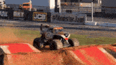 a monster truck is driving on a dirt track in front of a sign that says jcb