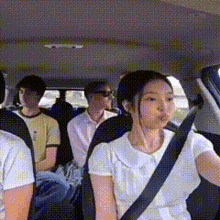 a group of people are sitting in the back seat of a car with a woman wearing a seat belt .