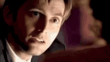 a man in a suit and tie is looking at a woman in a dark room .