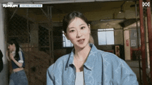 a woman in a blue jacket is standing in a room with a sign that says runup on it