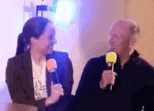 a man and a woman are talking into microphones while sitting next to each other .