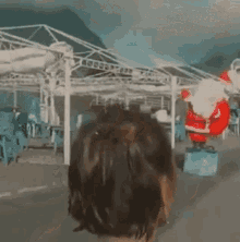a person is standing in front of a statue of santa claus on a beach .