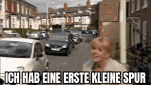 a woman is walking down a street in front of a row of cars .