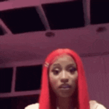 a woman with red hair is standing in front of a pink background .