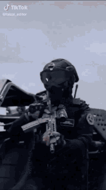 a soldier is holding a gun and wearing goggles and a mask .