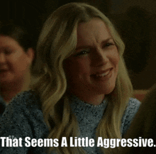 a woman in a blue sweater is smiling with the words that seems a little aggressive below her