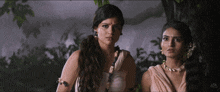 a couple of women standing next to each other with one wearing a necklace
