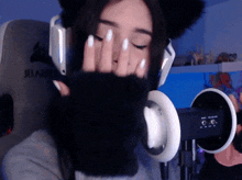 a woman wearing a cat ear headset is covering her face with her hands