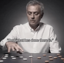 a man sitting at a table playing a game with the words " and what he 's done there is "