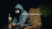 a man in a blue hoodie is sitting in a chair with the words goodbye boywithuke written above him