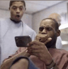 a man is getting his hair cut at a barber shop and looking at his phone .