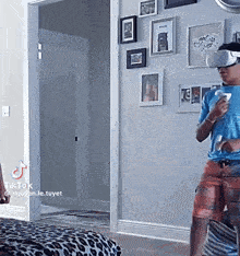 a man wearing a virtual reality headset is playing a video game in a living room