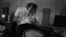 a black and white photo of a man playing drums in a room .