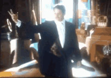 a man in a tuxedo and bow tie is standing in a room with his arms outstretched
