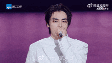 a man singing into a microphone with chinese writing on the bottom left