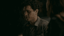 a man and a woman are standing next to each other in a dark room and looking at each other .
