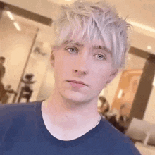 a young man with white hair and blue eyes is looking at the camera .