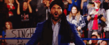 a man in a blue suit is standing in front of a crowd with a sign that says singh on it .