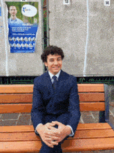 a man in a suit sits on a wooden bench in front of a sign that says peace