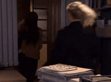 a woman walking into a dark room with a stack of papers on a cart