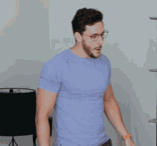 a man in a blue t-shirt is covering his nose with his hand