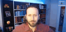 a man in a plaid shirt is standing in front of a bookshelf with a stream logo on the bottom