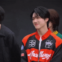 a young man wearing a red and black jacket is smiling .
