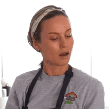 a woman wearing a headband and a gray shirt with a flower and rainbow embroidered on it