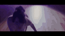 a person is standing in a dark room with a purple light coming out of the ceiling .