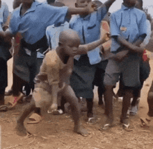 a group of children are dancing in a dirt field .