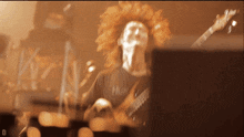 a blurred image of a man playing a guitar with the letter d on the bottom right