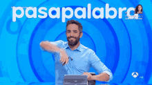 a man in a blue shirt is sitting in front of a screen that says pasapalabra