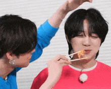 a man eating food with chopsticks while another man looks on