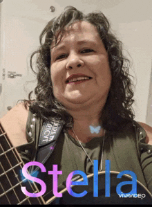 a woman holding a guitar with the name stella written on the bottom