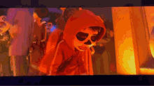 a person dressed as a skeleton in a red hoodie is standing in front of a fire .