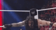 a wrestler is standing in the middle of a ring with his arms outstretched .