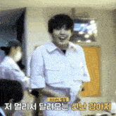 a man in a pink shirt is smiling in a room with foreign writing