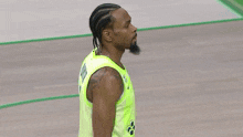 a basketball player in a neon yellow jersey is standing on a court .