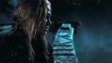 a woman with long blonde hair is looking at the camera in a dark room