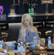 a woman with blonde hair is sitting at a table with a lot of food .