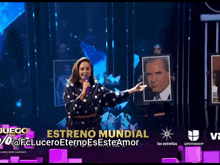 a woman is holding a picture of a man in front of a sign that says ' estreno mundial '