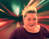 a woman in a purple shirt is smiling in front of a blurred background